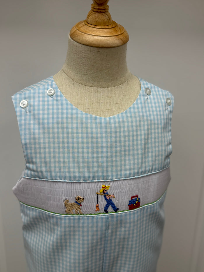 This Boys Gone Fishing Longall showcases a charming blue and white gingham pattern, highlighted by a detailed smocked fisherman &amp; his best friend embroidery on the front. Designed for comfort and style, it pairs perfectly with a classic Peter Pan collar shirt, creating an adorable and polished outfit ideal for playful days and special occasions.