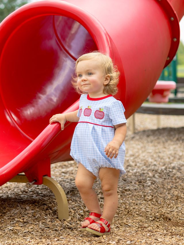 Brighten your little one’s day with the Apple Trio Bubble by Trotter Street Kids! This charming blue gingham bubble, decorated with playful red apple appliqués, adds a touch of fun and comfort to every outfit. Perfect for school days or playtime, it’s a delightful choice that sparks joy and style.