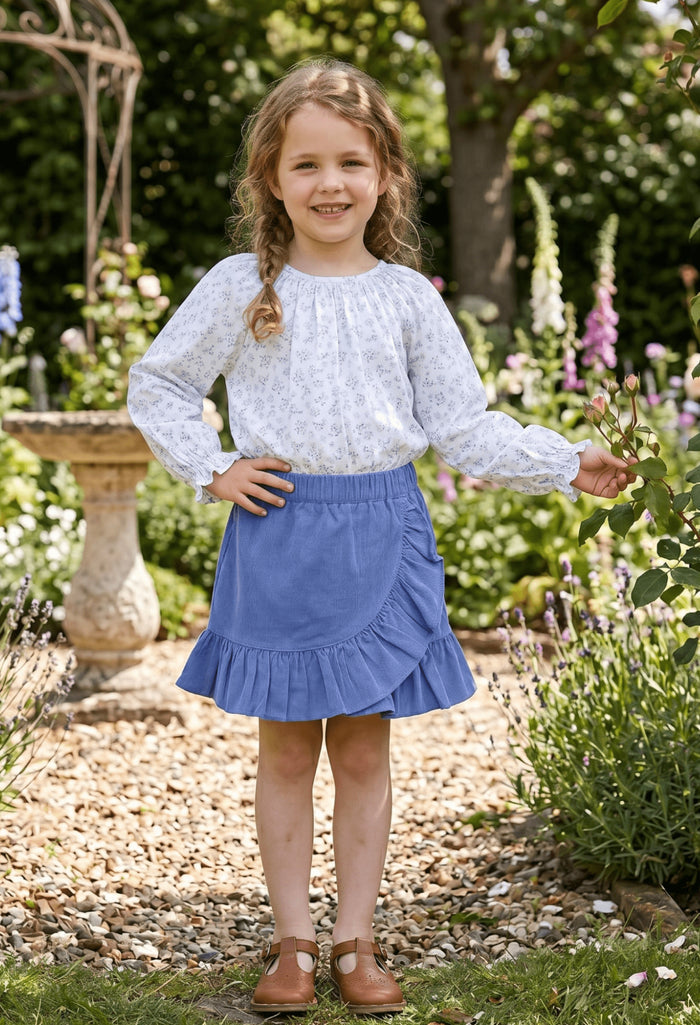 The Blue Blossom Elaine Blouse by Zuccini Kids brings joyful elegance to every moment. Its delicate blue floral pattern and charming ruffle neck collar add a touch of whimsy and grace, perfect for tween girls who want to shine with confidence and style.