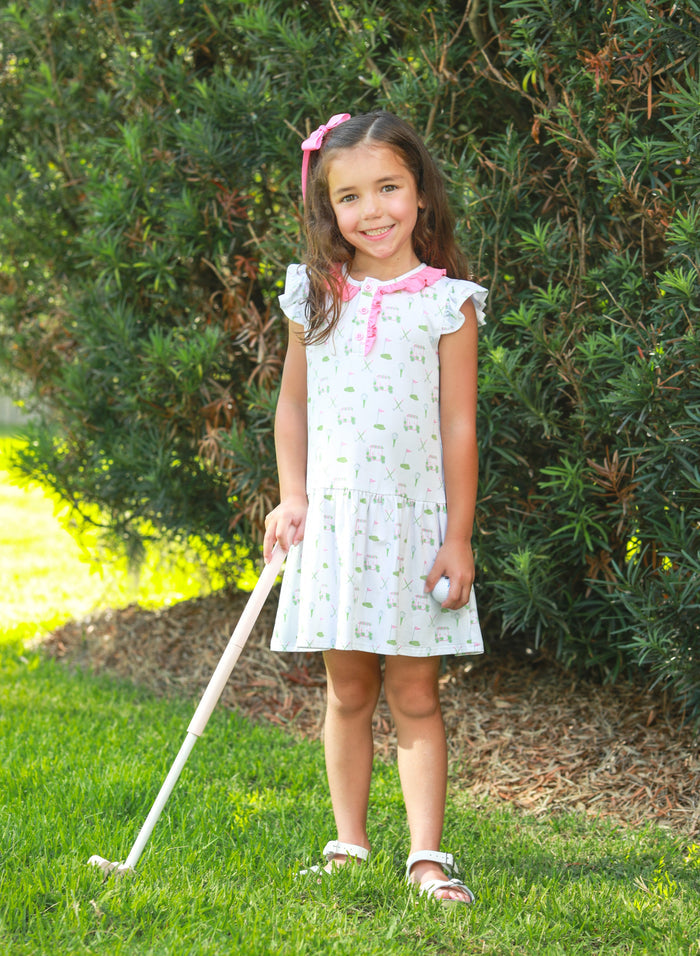 Introducing the Caddy Club Dress from Trotter Street Kids! This charming golf-printed knit dress features delightful ruffle sleeves and a playful drop hem, making it an ideal choice for spring and summer fun. With its breathable design and sweet pink trim, your little girl will feel both comfortable and stylish while enjoying her outdoor adventures. Embrace the joy of childhood with this delightful dress!