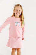 The Fair St Floral Bow Cassidy Comfy Crewneck by The Beaufort Bonnet Company combines cozy warmth with charming style. Its soft pink fabric, puff sleeves, and delicate floral bow create a timeless look perfect for tween girls’ school days and casual outings in cooler weather.