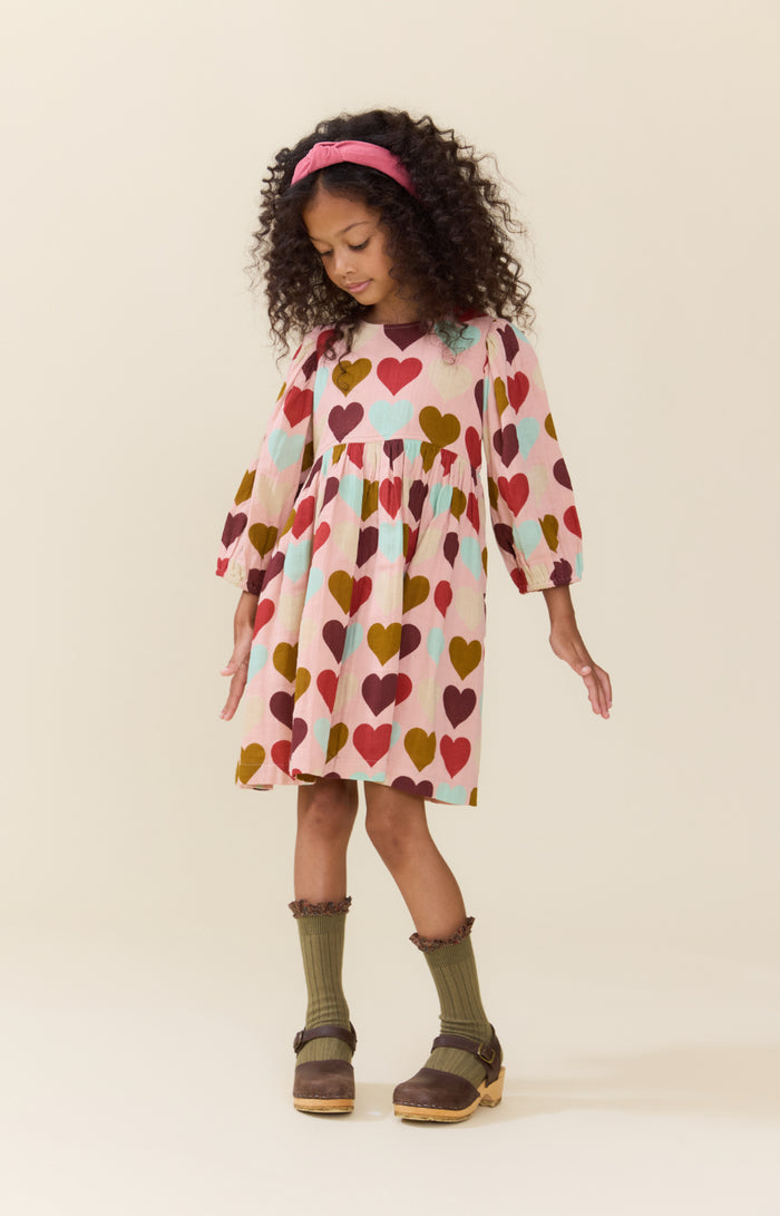 Pink Chicken’s Girls Bea Dress in Multi Harvest Hearts bursts with joyful colors that celebrate every moment. This vibrant dress brings playful charm and comfort to your tween’s wardrobe, making every day feel special and full of heart!