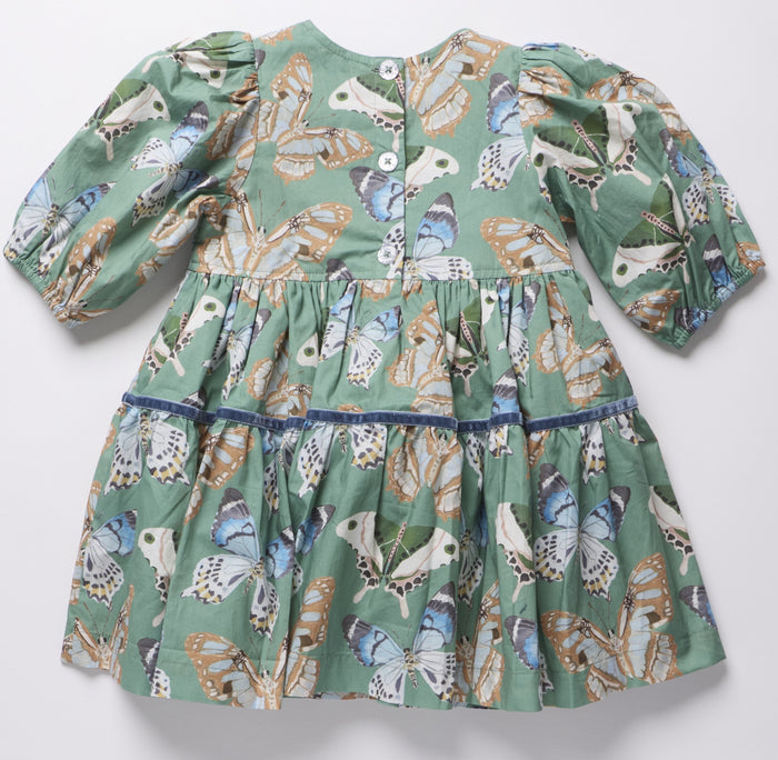 Pink Chicken’s Girls Maribelle Dress in Green Butterflies brings playful elegance to every twirl. The delicate butterfly print and navy velour ribbon trim create a charming look that delights and inspires confidence in every step. Perfect for joyful moments and unforgettable memories!