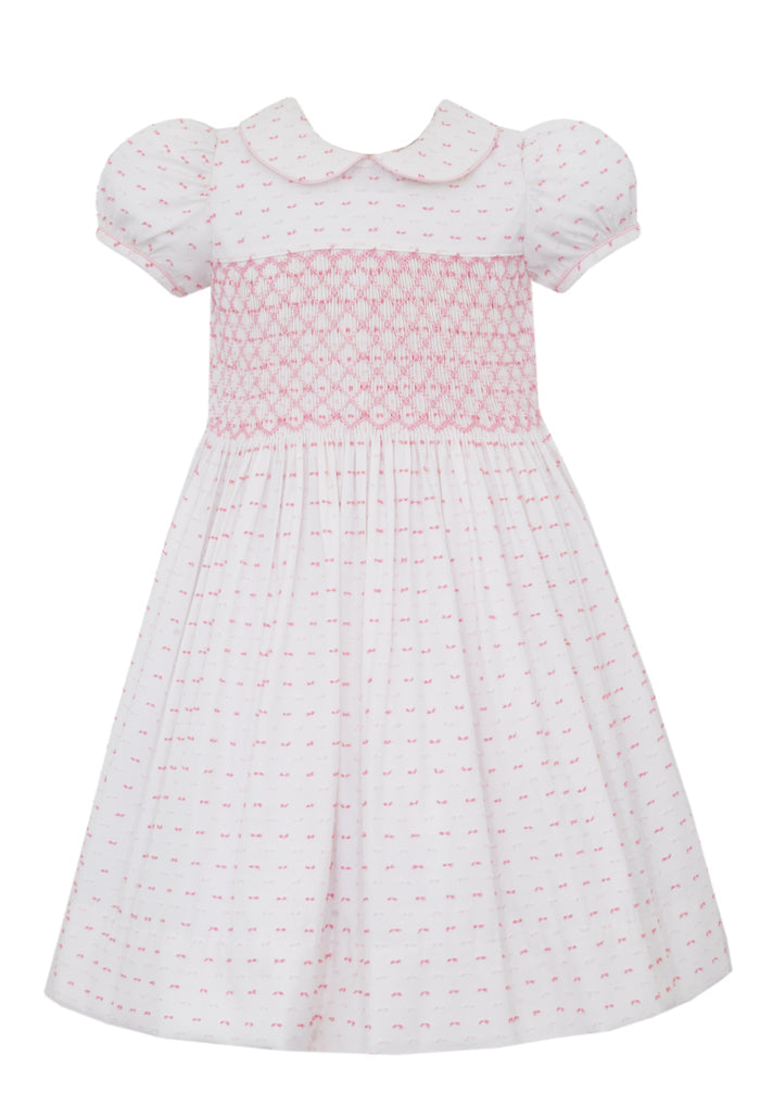Elevate your little girl's summer wardrobe with our Girls Pink &amp; White Dotted Plumeti Dress. With a smocked bodice and delicate hot pink dots on a crisp white background, this dress exudes timeless style and charm. Perfect for any occasion, its classic plumeti fabric is sure to make her stand out.