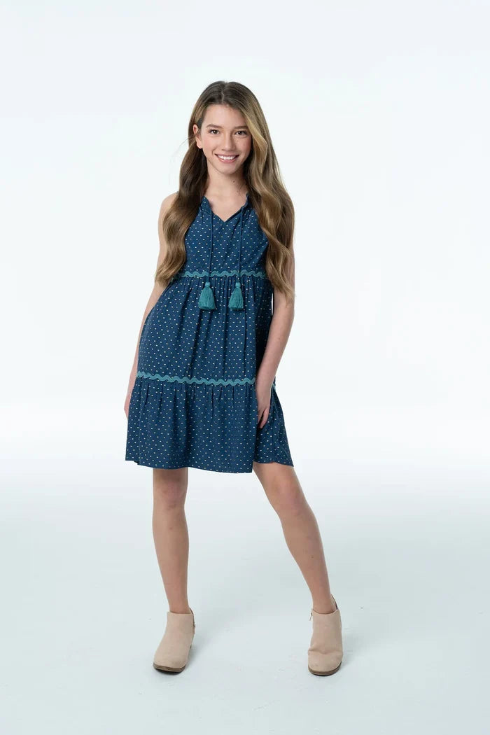 The Layla Dress in Crepe Polka Dot by Briton Court is a timeless silhouette designed for every special moment and everyday adventure! Crafted from lightweight crepe fabric in a classic navy polka dot print, this sweet dress features a tiered silhouette with delicate ric-rac trim, a flattering empire waist, and playful tassel ties at the neckline. Easy to dress up with boots or pair with sneakers for school and weekend outings, the Layla Dress is a versatile favorite she'll reach for all season long!