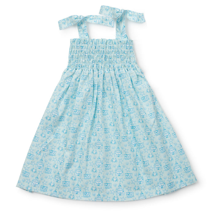 Get ready for some fun in the sun with the Sandcastles Blue Betsy Dress from Lila &amp; Hayes! This toddler dress features a vibrant ocean blue color with a playful sand castle design and comfortable smocked bodice. The tie straps add an extra touch of cuteness. Available in sizes 2t-6, this dress is perfect for a beach vacation.