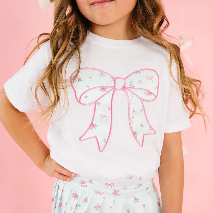 Elevate your little girl's wardrobe with this charming Sky Blue Floral Bow Patch Short Sleeve T-Shirt from Sweet Wink. The crisp white base showcases an eye-catching appliqué design featuring a delicate bow and vibrant floral print that captures playful sophistication. This versatile tee pairs beautifully with the coordinating Sky Blue Floral Pleated Skirt to create an effortless athleisure ensemble.
