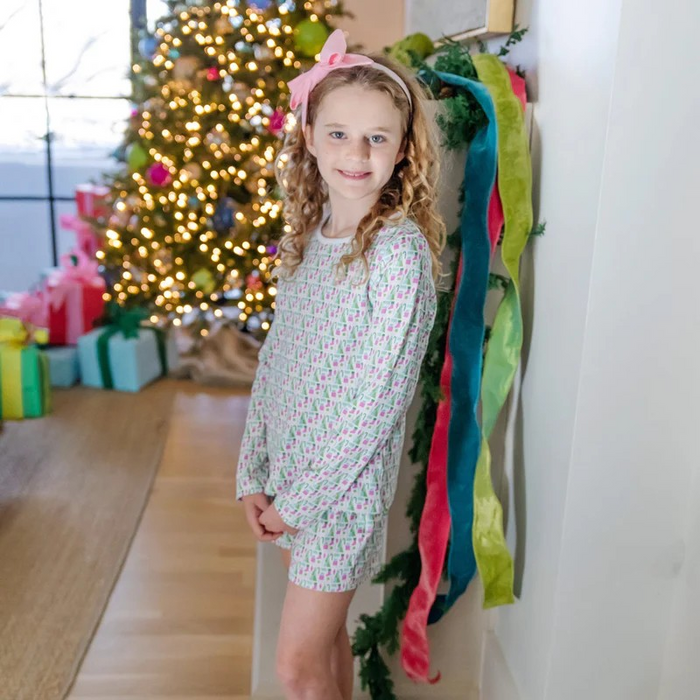 Keep her cozy and stylish this holiday with the Sophie Girls' Lounge Short Set in Mod Holiday Pink by Lila &amp; Hayes. This two-piece set features a long-sleeve top paired with comfortable shorts, designed for relaxed yet vibrant loungewear. The fun retro-inspired print adds a playful touch, making it perfect for festive gatherings or cozy days at home. Let her shine this season with a look that’s as cheerful as it is comfortable.