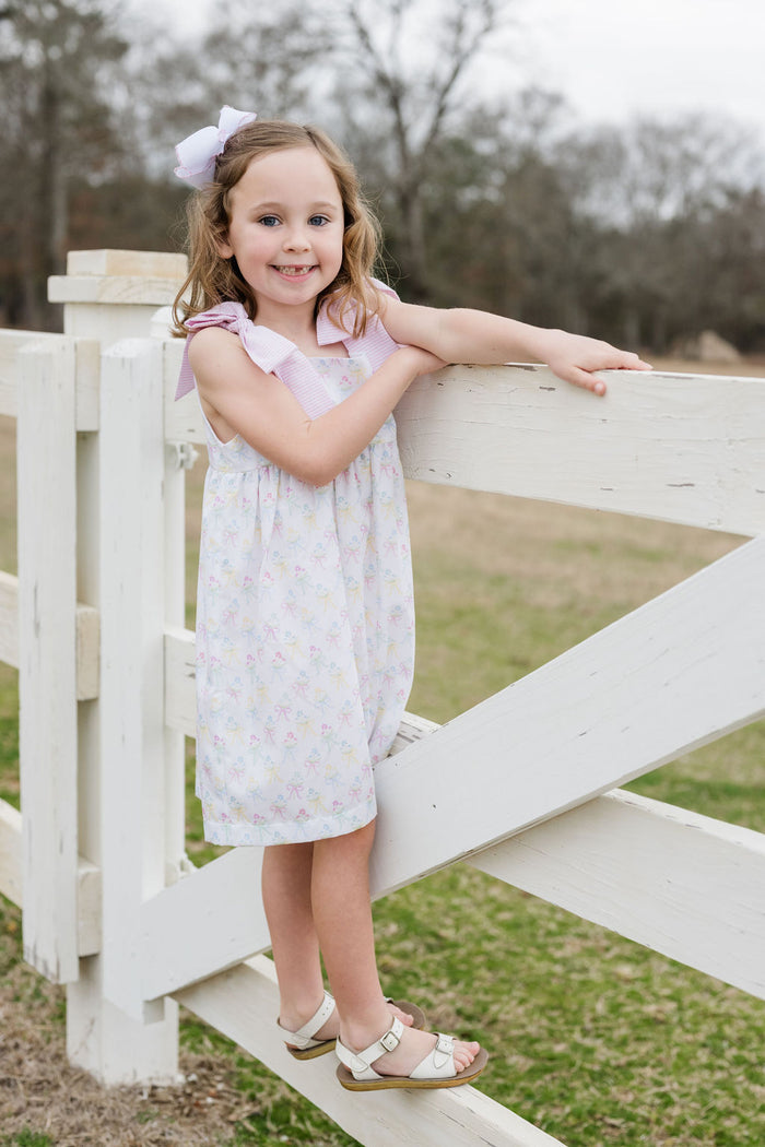 Indulge in the beauty of nature with Thea Flower Bouquet Dress from James &amp; Lottie! Adorned with floral bouquets and cute bows, this dress exudes a sense of elegance. The pink and white seersucker ties on the shoulders add a charming touch. Perfect for any occasion, this dress will make you feel like a blooming flower!